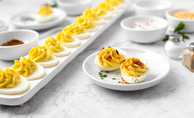 Close-up of Deviled Eggs with a Deviled Egg Bar behind on a Marble Countertop