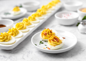 Close-up of Deviled Eggs with a Deviled Egg Bar behind on a Marble Countertop