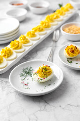Close-up of Deviled Eggs with a Deviled Egg Bar behind on a Marble Countertop