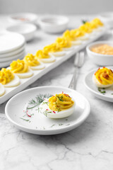Close-up of Deviled Eggs with a Deviled Egg Bar behind on a Marble Countertop