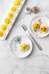 Top View of Deviled Eggs on a White Plate on a White Marble Countertop