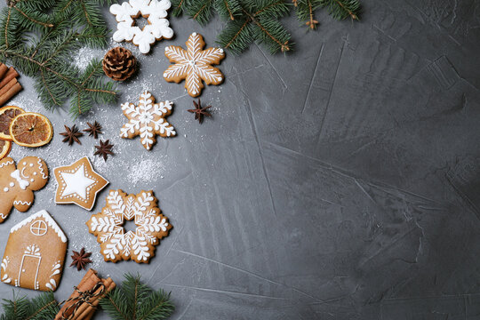 Decorated Christmas cookies and fir tree branches on grey table, flat lay. Space for text