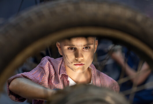 Boy looking at a wheel from a motorcycle. Sigth. Mechanic. Face