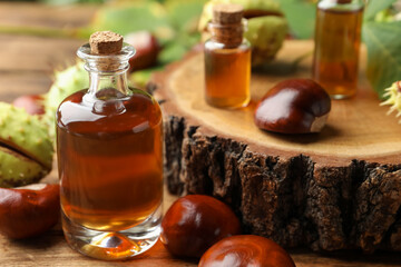 Fototapeta na wymiar Chestnuts and bottles of essential oil on wooden table, closeup