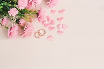 Pair of wedding rings surrounded by hearts and flowers. Top view with copy space