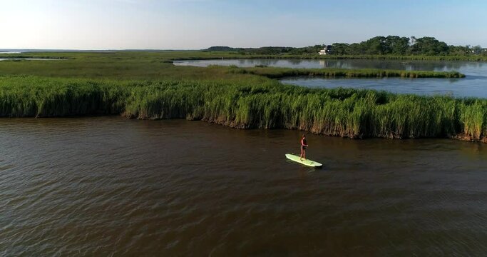 Young woman paddle boarding on the sound in the Other Banks, North Carolina, Aerial Drone Shot