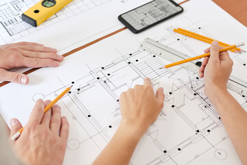 Hand of young female engineer with pencil pointing at sketch of new building