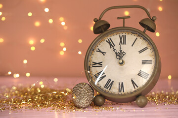 Fototapeta na wymiar Vintage clock with decor on pink table against blurred Christmas lights, closeup. New Year countdown