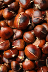 Pile of delicious edible roasted chestnuts as background, top view