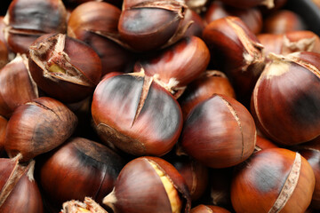 Pile of delicious edible roasted chestnuts as background, closeup
