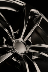 Black Gloss alloy wheel on a dark background. Stylish and expensive. Close-up of spoke elements,...