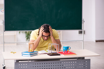 Young male student physicist preparing for exams in the classroo