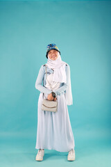 Fashion photo of a beautiful elegant young asian woman holding handbag posing over blue background.