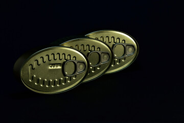 dark photo of three food canning cans on black background