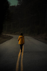 Woman in a yellow jacket walking on the road