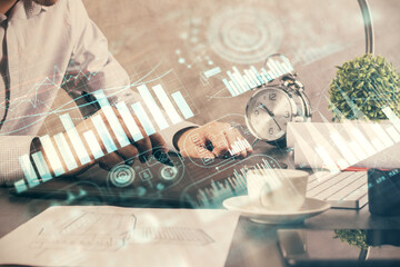 Double exposure of man's hands holding and using a phone and financial graph drawing. Analysis concept.