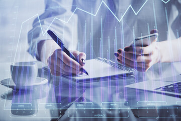 Double exposure of financial graph sketch hologram and woman holding and using a mobile device. Stock exchange concept.