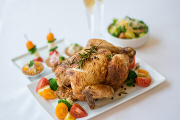 Whole roasted chicken and side dishes on white plate