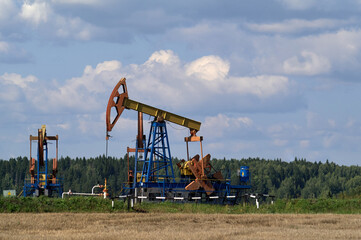 Fototapeta na wymiar Two oil pumps. Oil industry equipment in agricultural field