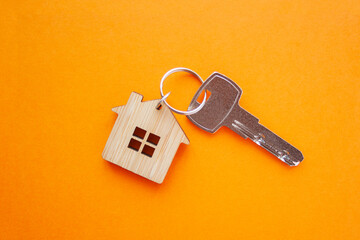 Key and house shaped keychain arrangement on orange background. Top view, flat lay. Real estate, insurance concept, mortgage, buy sell house, realtor concept. - obrazy, fototapety, plakaty