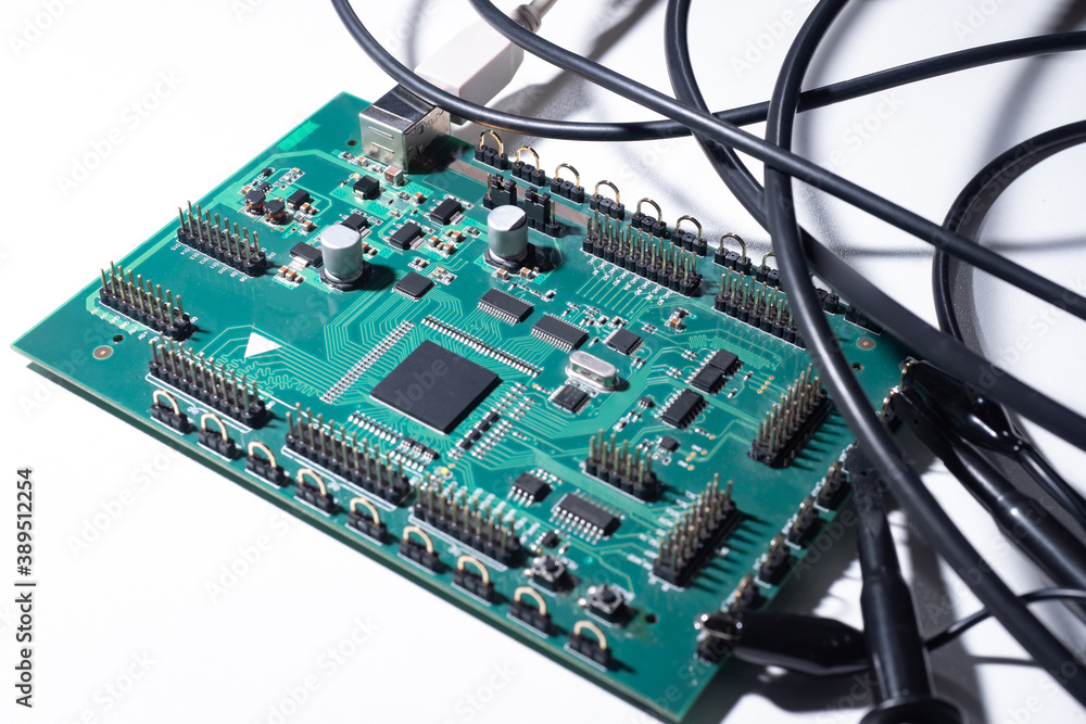 Poster wires are connected to the pcb. concept - pcb testing. circuit board on a white table. lots of wires