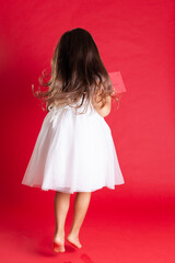 full length back girl in a white wedding dress runs to give a gift for Christmas or birthday on a scarlet background.