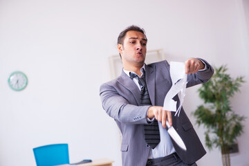 Young employee angry with excessive work holding knife