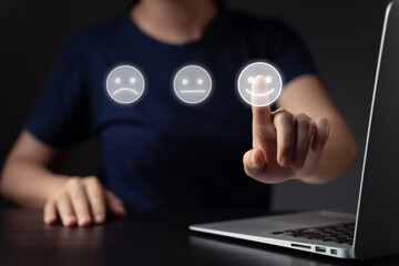 Woman using laptop and emoticon hologram effect.