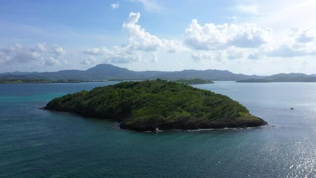 island in the ocean Martinique rocky islet  with tropical trees aerial shot windy area 