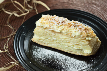 Fresh delicious cake napoleon with cream on a dark background.