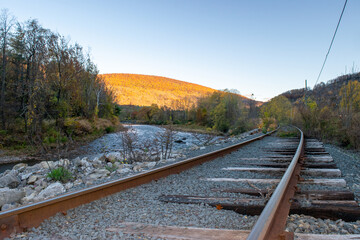 Curving Railroad Tracks in Mountains with River in Autumn