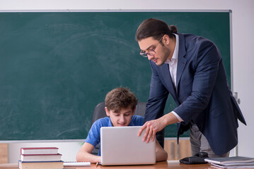 Young male teacher and schoolboy in the classroom