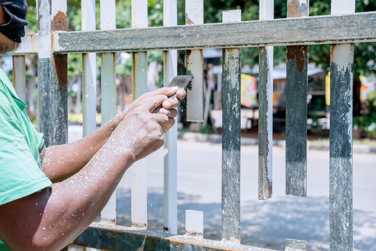 Worker Hands Peel Off Paint Of Fence With Putty Knife