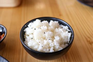 Jasmine rice with black sesame in black cup on wooden background.