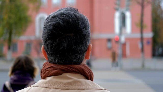 A man waits for a traffic light and crosses the road when the light turns green. Crossing the road according to the traffic rules.