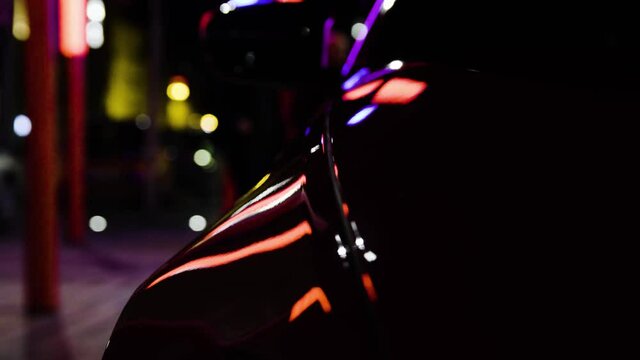 Detail closeup rear carbon fiber reflections in red sport car in the dark night in the city standing static