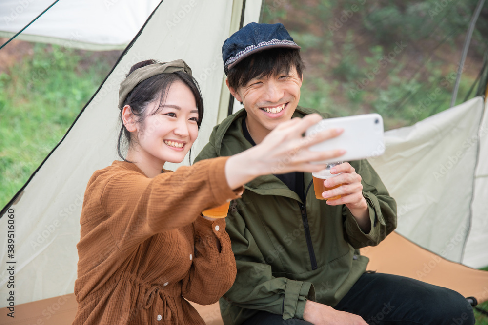 Poster キャンプでスマホを見る男女
