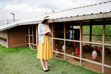 Farmer woman checking chicken in domestic coop. © THESHOTS.CO