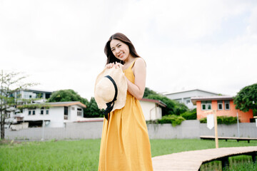 Obraz premium Beautiful asian traveler woman hold hat standing on wooden bridge across rice field.