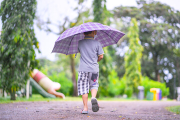 child with umbrella walking in the rain