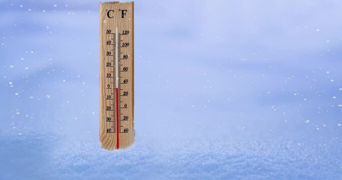 Measuring cold temperature with a wooden thermometer during snow storm.