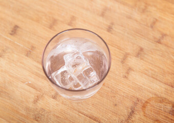 Looking down on a glass of clear water with ice on the table