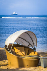 sheltered beach lounge chair with overhead cover on a topical beach by the sea