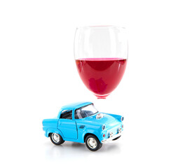 A glass of wine and a small car model on a white background