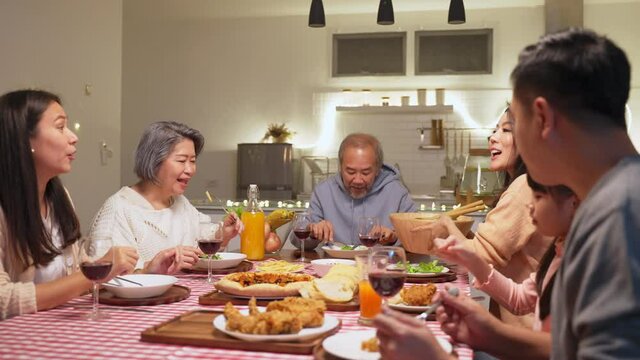 Group of Asian big family having dinner party together in the kitchen.