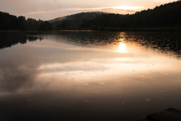 A beautiful view by the lake during sunset on a summer evening. Forest lake with mountains around
