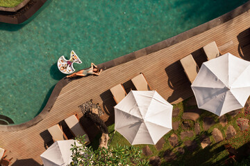 Enjoying suntan. Vacation concept. Top view of young woman near the swimming pool, floating...