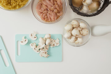Fresh raw  chopped organic white mushrooms close up on cutting board on white background, directly from above
