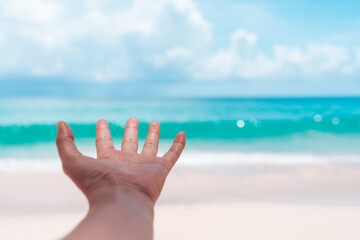 Woman hands reach out to the beach or blue sea.