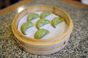 Steamed vegetarian dumplings filled with black fungus, mushrooms, vermicelli, beancurd cubes, served in bamboo basket, Chinese dim sum.